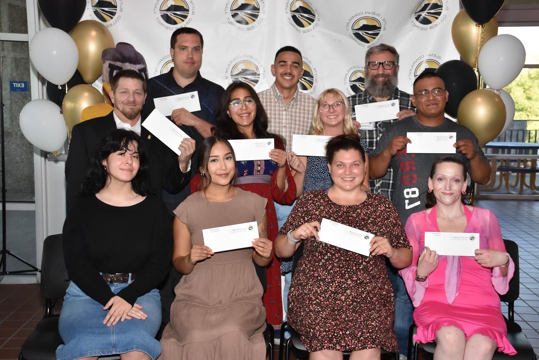 a gruop of students poses together hold scholarship checks. 